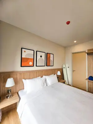a bedroom with a white bed with three pictures on the wall at Wora Phuket in Ban Sam Kong