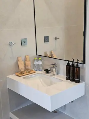 a white bathroom sink with a large mirror at Wora Phuket in Ban Sam Kong