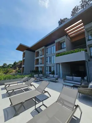 a group of chairs and lounge chairs in front of a building at Wora Phuket in Ban Sam Kong