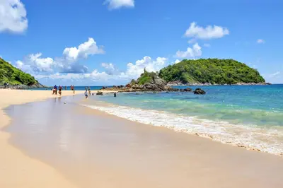 a beach with people walking on the sand and the ocean at Duplex 1 BR UTL B131 - Relax and Play in Rawai Beach