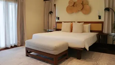 a bedroom with a large white bed with a ottoman at \u666e\u5409\u9ad8\u7aef\u5eb7\u517b\u6cf3\u6c60\u522b\u5885 in Layan Beach