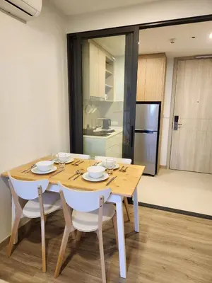 a wooden table with white chairs and a kitchen at Skypark Laguna Apartment with Rooftop Pool at Bang Tao Phuket in Laguna Phuket