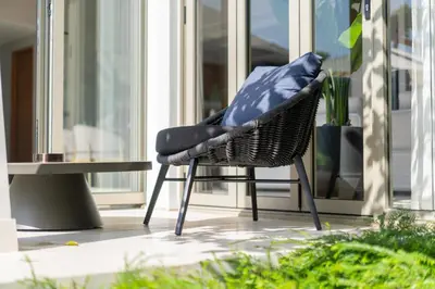a chair with a blue pillow sitting on a porch at Luxury Royale Bangtao Pool Villa with maid in Thalang