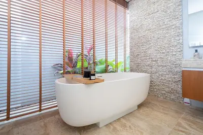 a bath tub in a bathroom with a large window at Luxury Royale Bangtao Pool Villa with maid in Thalang