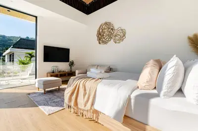 a white bedroom with a bed and a tv at Aileen Naithon Hills - Tropical Haven Retreat in Nai Thon Beach