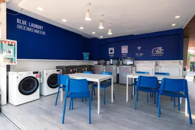 a laundry room with tables and blue chairs and washing machines at The Beach Residence Kata in Kata Beach