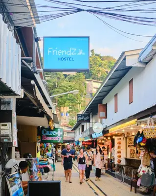 a group of people walking down a street in a market at Friendz Hostel in Phi Phi Don
