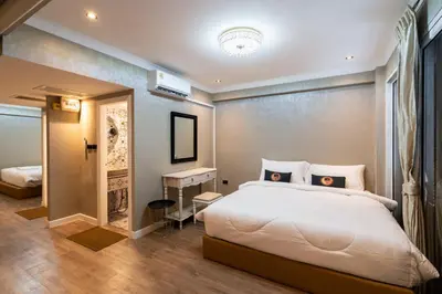 a bedroom with a large white bed and a desk at RQ Timeless Phuket Old Town in Phuket Town