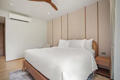 a bedroom with a large white bed and a ceiling at Laguna Beach Residences Seashore by Banyan Living in Thalang
