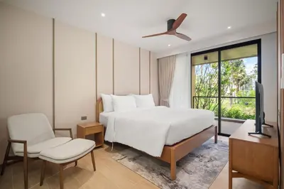 a bedroom with a bed and a tv and a window at Laguna Beach Residences Seashore by Banyan Living in Thalang