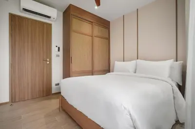 a bedroom with a large white bed and a wooden door at Laguna Beach Residences Seashore by Banyan Living in Thalang