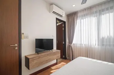 a bedroom with a television on a dresser and a bed at Laguna Parkside Residences by Banyan Living in Phuket Town