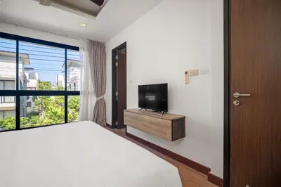 a bedroom with a bed and a flat screen tv at Laguna Parkside Residences by Banyan Living in Phuket Town