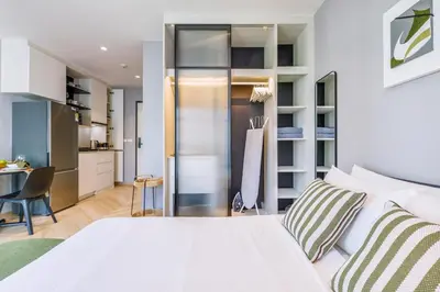 a bedroom with a white bed and a kitchen at Tropical studio Luxury Amenities and Pool in Bang Tao Beach