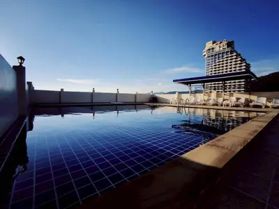 a pool with chairs and a building in the background at 3-bedroom apartment, Patong, Palm Spring 602 in Patong Beach