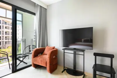 a living room with a chair and a bedroom at Bangtao The Title Legendary by Phuket Sabay Rent G402 in Bang Tao Beach