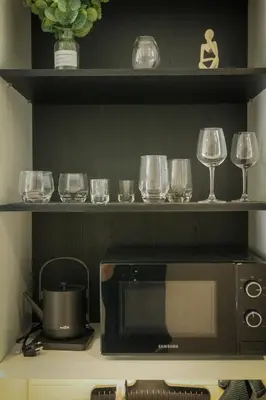 a kitchen with a microwave and wine glasses on a shelf at Bangtao The Title Legendary by Phuket Sabay Rent G402 in Bang Tao Beach