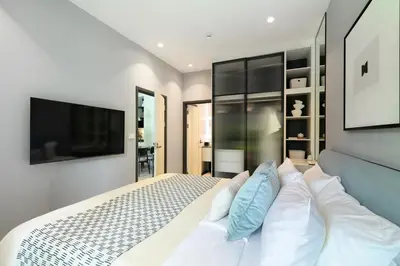 a bedroom with a white bed and a television at Bangtao The Title Legendary by Phuket Sabay Rent C108 in Bang Tao Beach