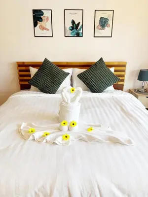 a bed with white towels and yellow flowers on it at Sachi Home Bangtao -Private House Near Beach in Ban Thalat Choeng Thale