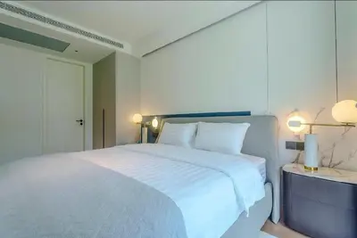 a bedroom with a white bed with two lamps and a door at Two Bedroom Sea View by Triple 8 Asia in Layan Beach