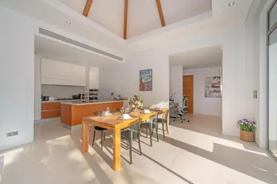 a kitchen and dining room with a wooden table and chairs at Thai-Balinese Pool Villa Anchan Indigo16 in Ban Phru Champa
