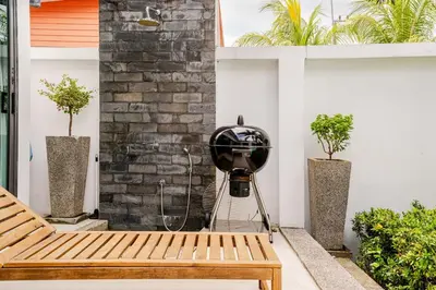 a patio with a bench and a fan next to a brick wall at Baan Araya by Villacarte in Ban Saiyuan (1)