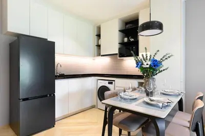 a kitchen with a table and a black refrigerator at Bangtao The Title Legendary by Phuket Sabay Rent A212 in Bang Tao Beach