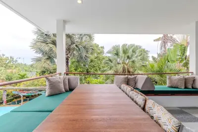 a balcony with a wooden table and pillows at V89 6BR Timeless Design Huge Pool & Mountain View in Rawai Beach
