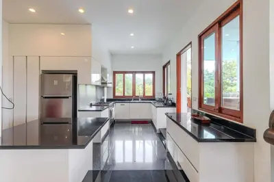 a large kitchen with white cabinets and black counter tops at V89 6BR Timeless Design Huge Pool & Mountain View in Rawai Beach