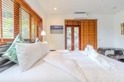 a large white bed in a room with windows at V89 6BR Timeless Design Huge Pool & Mountain View in Rawai Beach