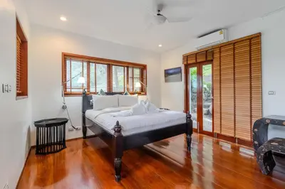 a bedroom with a bed and wooden floors and windows at V89 6BR Timeless Design Huge Pool & Mountain View in Rawai Beach