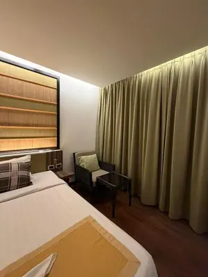 a hotel room with two beds and a chair and curtains at The Beach Condotel Kata in Kata Beach