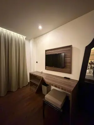a hotel room with a desk with a television on the wall at The Beach Condotel Kata in Kata Beach
