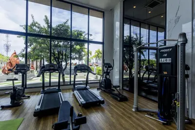 a gym with treadmills and ellipticals in front of a window at Mida Grande Ocean View in Surin Beach