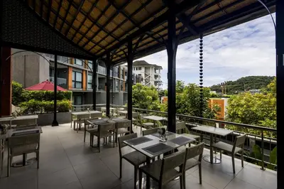 a restaurant with tables and chairs on a balcony at Mida Grande Ocean View in Surin Beach