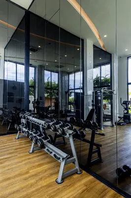 a gym with rows of tread machines and mirrors at Mida Grande Ocean View in Surin Beach