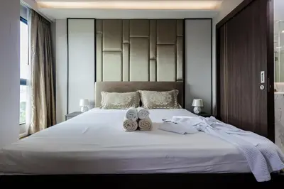a bed with two pairs of shoes and towels on it at Mida Grande Ocean View in Surin Beach