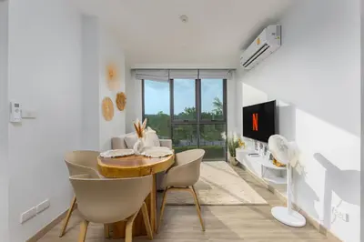 a living room with a wooden table and chairs at Melia 2BR with Rooftop Pool - Skypark Laguna in Laguna Phuket