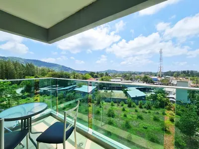 a large glass balcony with a table and chairs at BP Sweet Home Bang Tao - 607 in Ban Thalat Choeng Thale