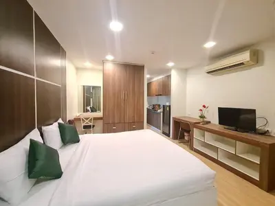 a bedroom with a large white bed with green pillows at BP Sweet Home Bang Tao - Studio in Ban Thalat Choeng Thale