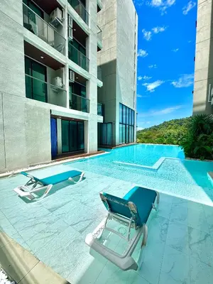 a swimming pool with two lounge chairs next to a building at 1BR Patong Hideaway - Pool - Near Beaches - A403 in Patong Beach