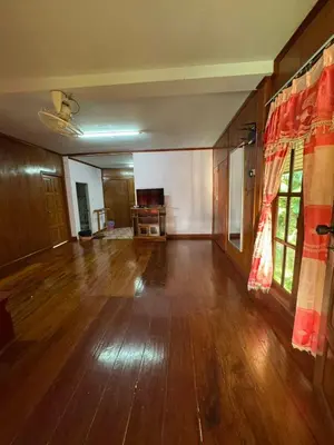 an empty living room with wooden floors and curtains at Family house in Ban Laem Sai