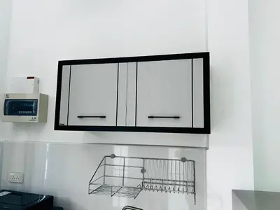 a kitchen with white cabinets and a microwave at Sarona House 4 in Ban Thalat Choeng Thale