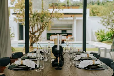 a wooden table with plates and glasses and candles at Botanica Foresta B09 in Ban Phru Champa