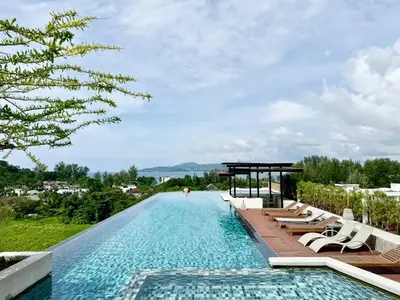 a pool at a resort with lounge chairs and trees at Stylish 1BR Surin Beach Kitchen & Rooftop Pool by Renttini in Ban Lum Fuang
