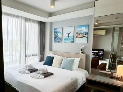 a bedroom with a large bed with two towels on it at Stylish 1BR Surin Beach Kitchen & Rooftop Pool by Renttini in Ban Lum Fuang