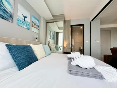 a bedroom with a white bed with towels on it at Stylish 1BR Surin Beach Kitchen & Rooftop Pool by Renttini in Ban Lum Fuang