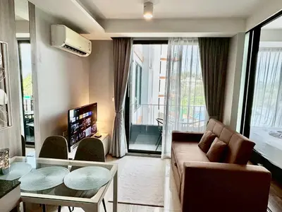a living room with a couch and a table at Stylish 1BR Surin Beach Kitchen & Rooftop Pool by Renttini in Ban Lum Fuang