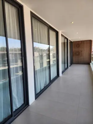 an empty hallway in a building with windows at Sunshine Beach Appartments, 2BD in Layan Beach