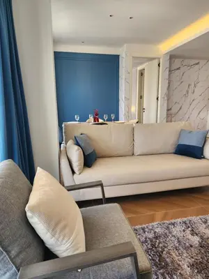 a living room with a couch and a blue wall at Sunshine Beach Appartments, 2BD in Layan Beach